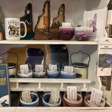 Display of handcrafted candles and wooden art on shelves in a store.