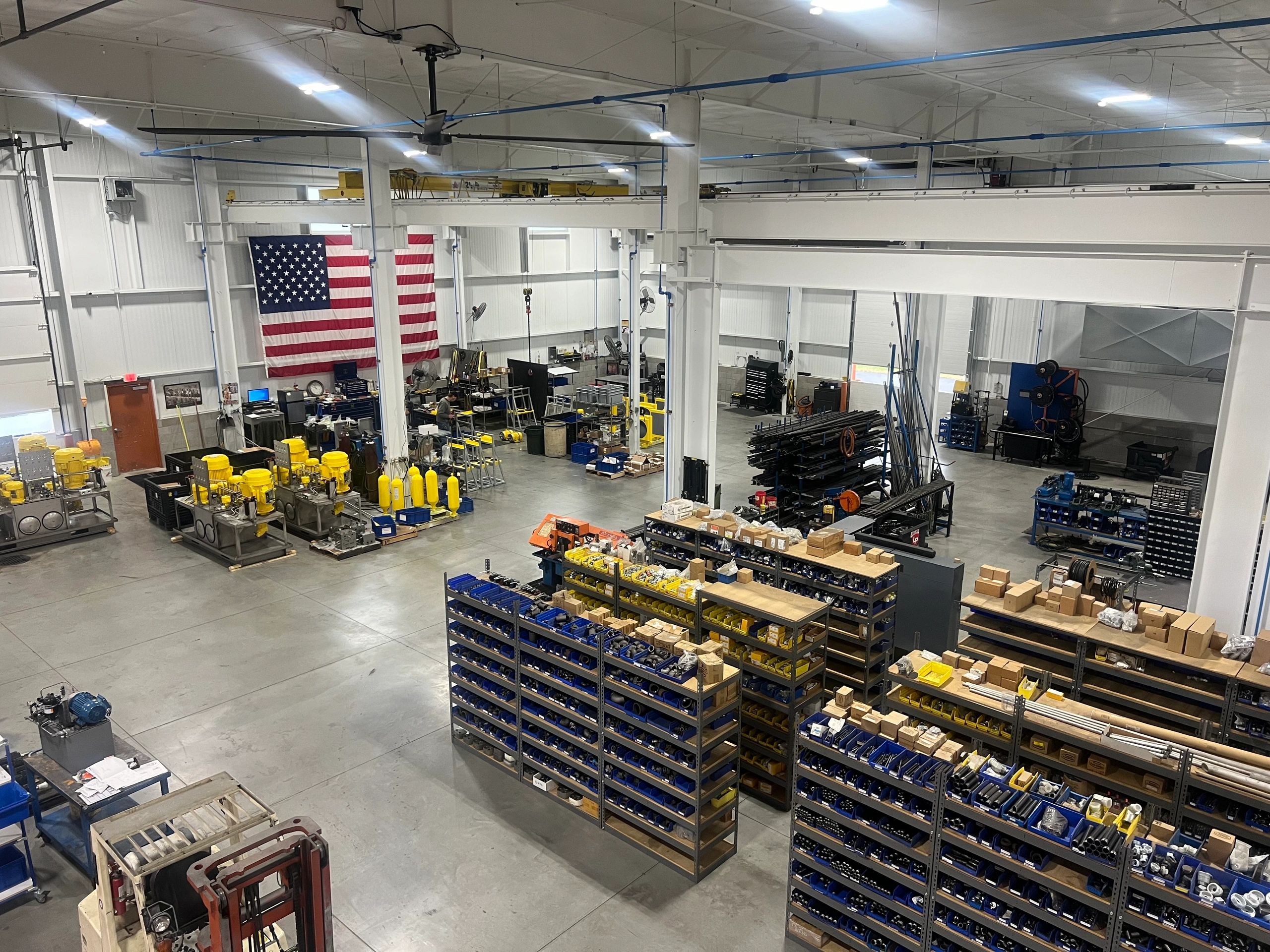 Picture of warehouse showing shelves of products. 
American flag proudly hangs on the warehouse wall