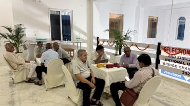 Group of men sitting around tables in a hall.