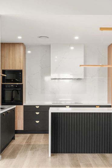 Modern kitchen with black cabinets, wood accents, and white marble backsplash.