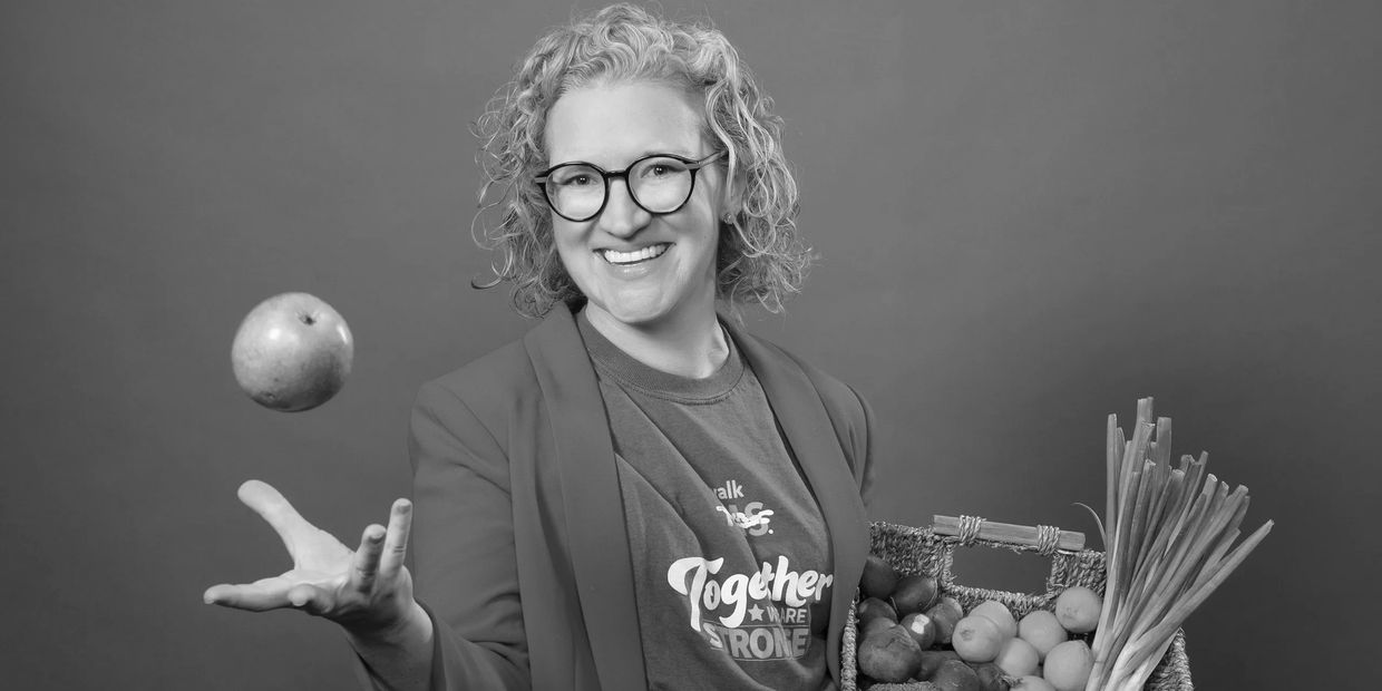 Katie Fletcher smiling while throwing an apple in the air