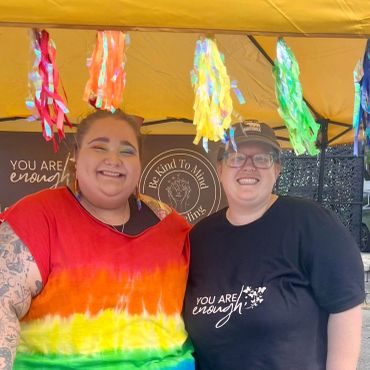 Two smiling people under a yellow canopy with colorful decorations.