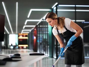 A woman wearing gloves mopping an office floor.