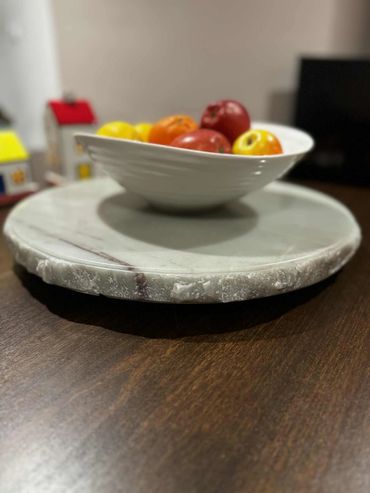 White bowl with fruits on a marble tray on a wooden table.