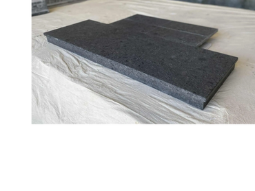 Dark stone slab with a notch, placed on a light fabric surface.