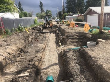 Construction workers excavating a trench on a residential street.