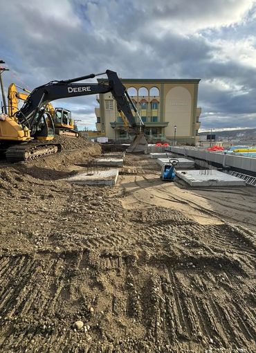Construction site with excavators near a city hall building under cloudy sky.