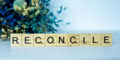 Wooden tiles spell 'RECONCILE'.