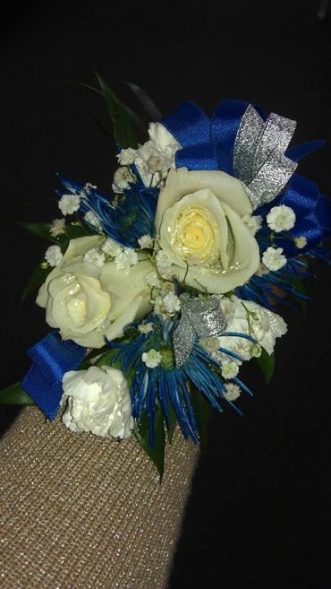 A white rose corsage with blue and silver ribbon