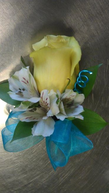 A yellow rose boutonniere with small white lilies