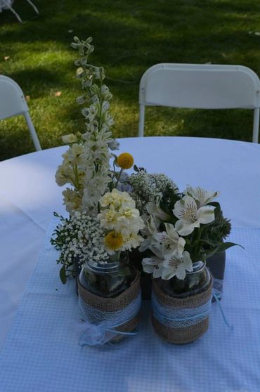 A centerpiece with yellow flowers on a white table