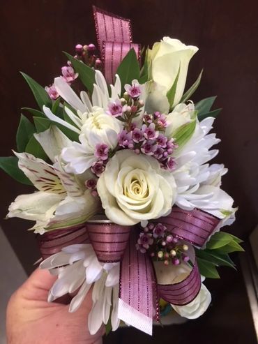 A white and purple corsage with ribbon