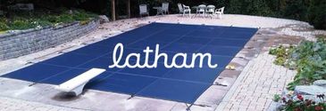 A covered swimming pool with a dive board and patio furniture.