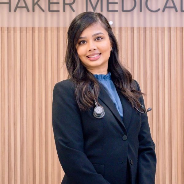 Dr. Mayuri Kinkhabwala wearing a blue coat standing in front of a Shaker Medical Group sign.