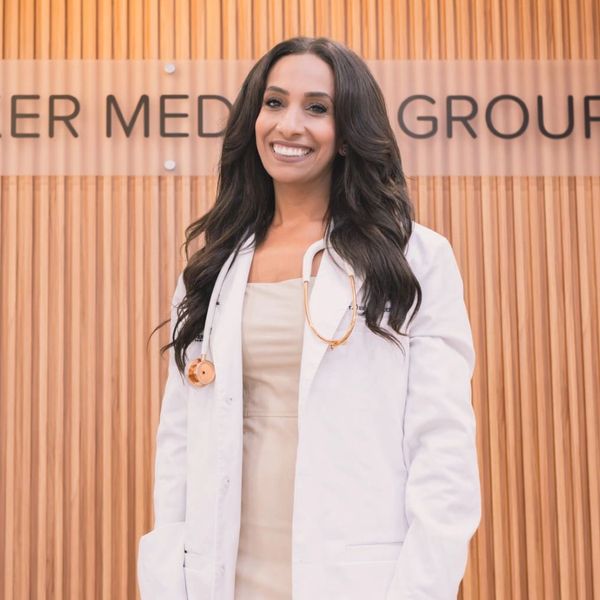 Close up of Dr. Miriam Hanna wearing a white coat standing in front of a Shaker Medical Group sign.