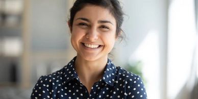 Cheerful Indian girl standing at home looking at camera.