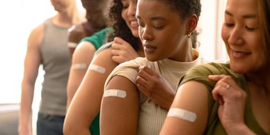 Group of diverse female and male friends showing plasters after vaccination.