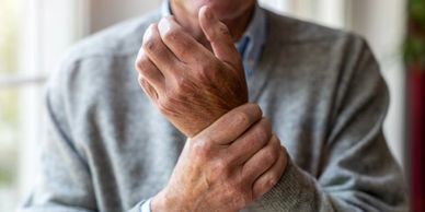 A close up on the hands of a senior male holding them together as if he's in pain.