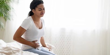 Sick woman suffering from acute abdominal pain at home.