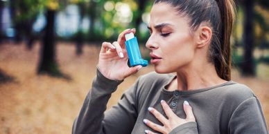 Young woman treating asthma with inhaler.
