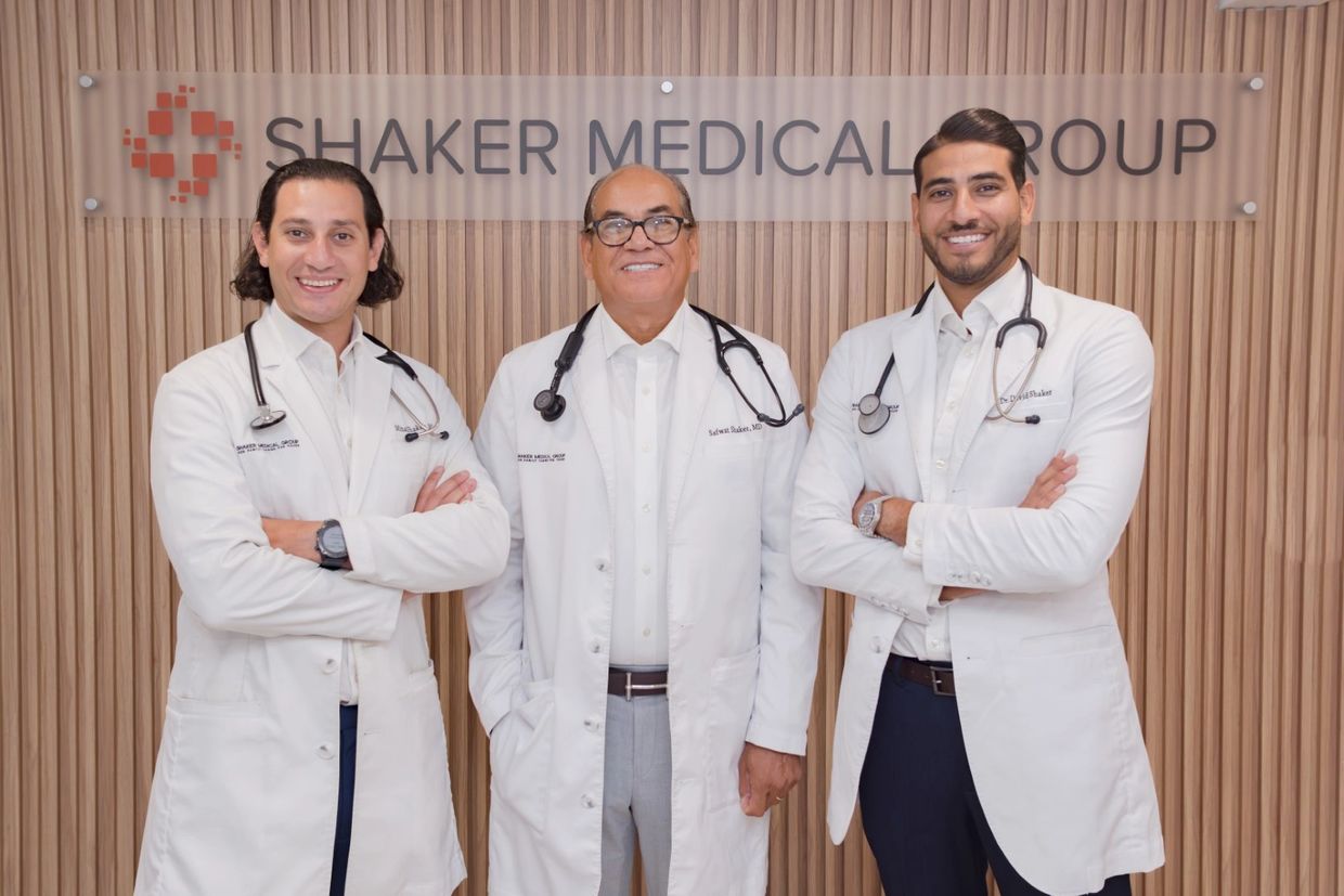 Doctors Safwat, Mina, and David Shaker stand in front of a sign that reads Shaker Medical Group.