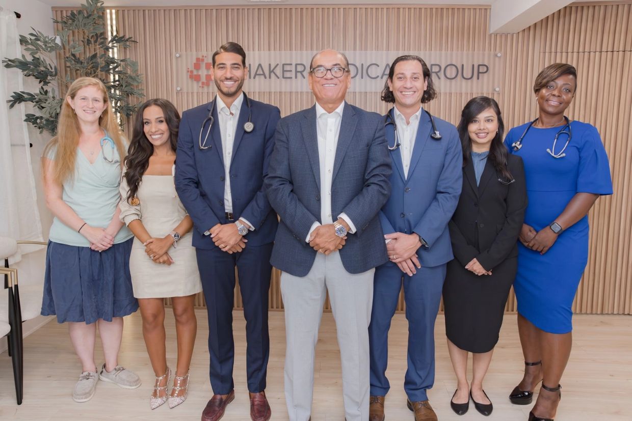 The men and women that staff Shaker Medical Group stand close together, smiling.