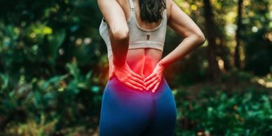 Female wearing exercise clothing grabs at her lower back in pain.