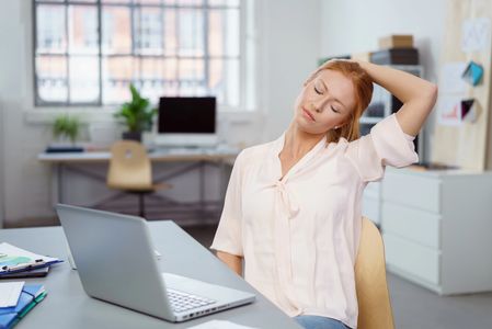 Prairie Chiropractic Patient performing neck stretches at desk.