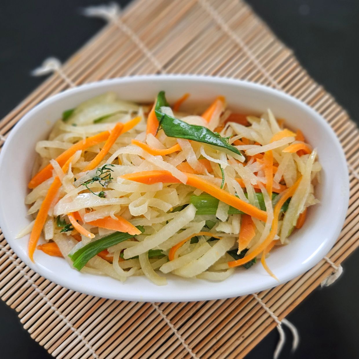 A bowl of fresh mixed vegetable salad with carrots and greens.