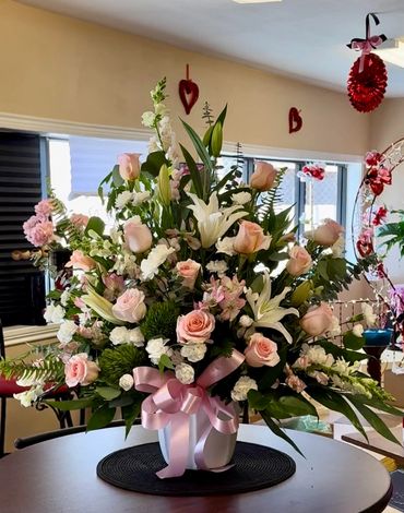 Blush Pink Roses, White Lilies, Snap Dragons and Assorted Flowers in table top container. one sided