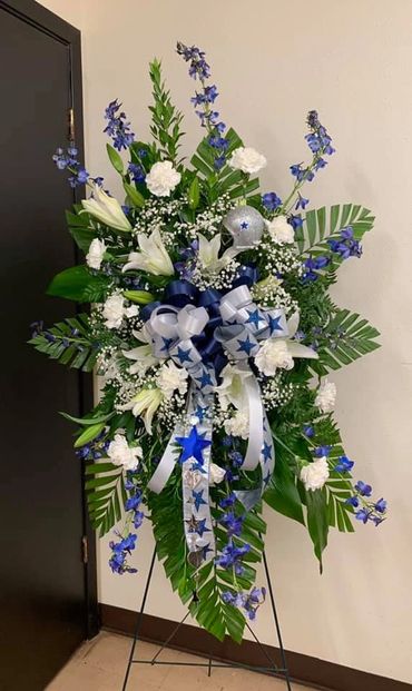 Dallas Cowboy theme Spray with white carnations and lilies. Blue Delphinium, and assorted Greens.