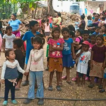 Group of children standing outdoors in a rural setting.