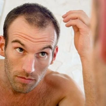 Man looking at his hair loss in a mirror