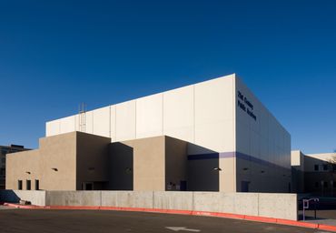 Modern school building with geometric design and smooth stucco exterior under a clear blue sky.