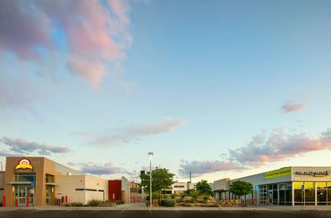 Calibers, The Daily Grind, and Los Pinos Fly Shop with modern architecture under a soft evening sky.