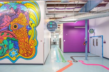 Colorful interior hallway at Deluxe Design with vibrant mural and wayfinding graphics.