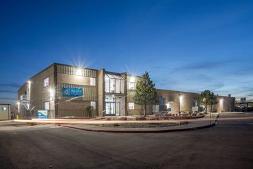 Deluxe Design building illuminated at dusk with modern industrial façade and glass entry.