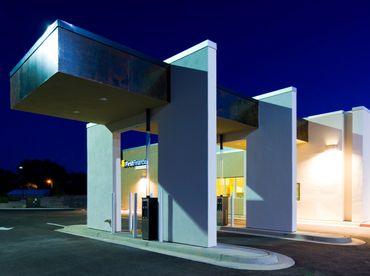 Drive-thru canopy with modern lighting and clean minimalist design against a twilight sky.