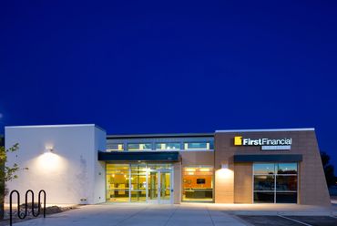 Contemporary building with warm interior lighting and angular façade set against a deep blue sky.