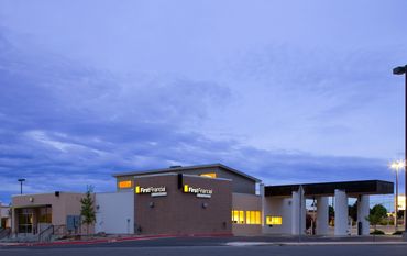 Modern structure with soft evening lighting, drive-thru canopy, and clean linear rooflines.