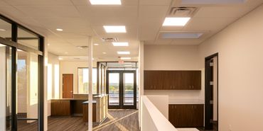 Open office interior with glass walls, wood cabinetry, natural lighting from clerestory and doors.
