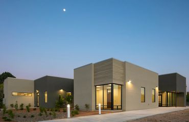 Contemporary office building with geometric volumes, clean stucco finish, and expansive glass entry.