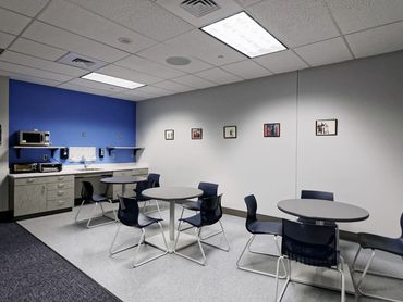 Employee break room with tables, blue accent wall, and kitchenette at Denver International Airport.