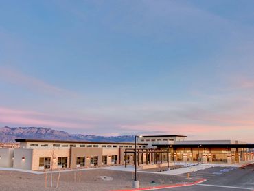 Modern senior care facility with mountain views, clerestory windows, and covered entry at sunset.