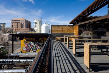 Marble Brewing rooftop deck with wood seating, shade structures, and downtown Albuquerque views.