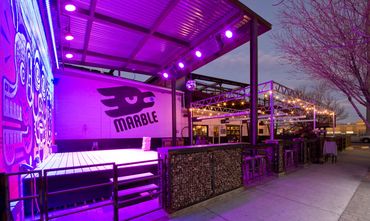Marble Brewing outdoor stage and patio seating with purple lighting in Albuquerque, New Mexico.