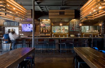 Marble Brewing's interior bar with wood accents, chalkboard menus, and warm ambient lighting.
