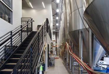 Interior view of Marble Brewing’s production area featuring steel stairs and fermentation tanks.