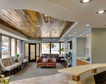 Dental office lobby with wood ceiling design, natural light, and comfortable modern seating.