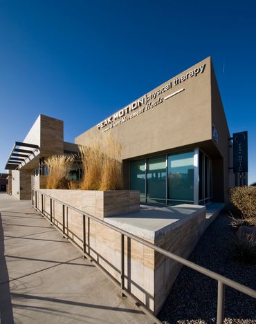 Angular modern building exterior with stone planters and metal accents under a clear blue sky.